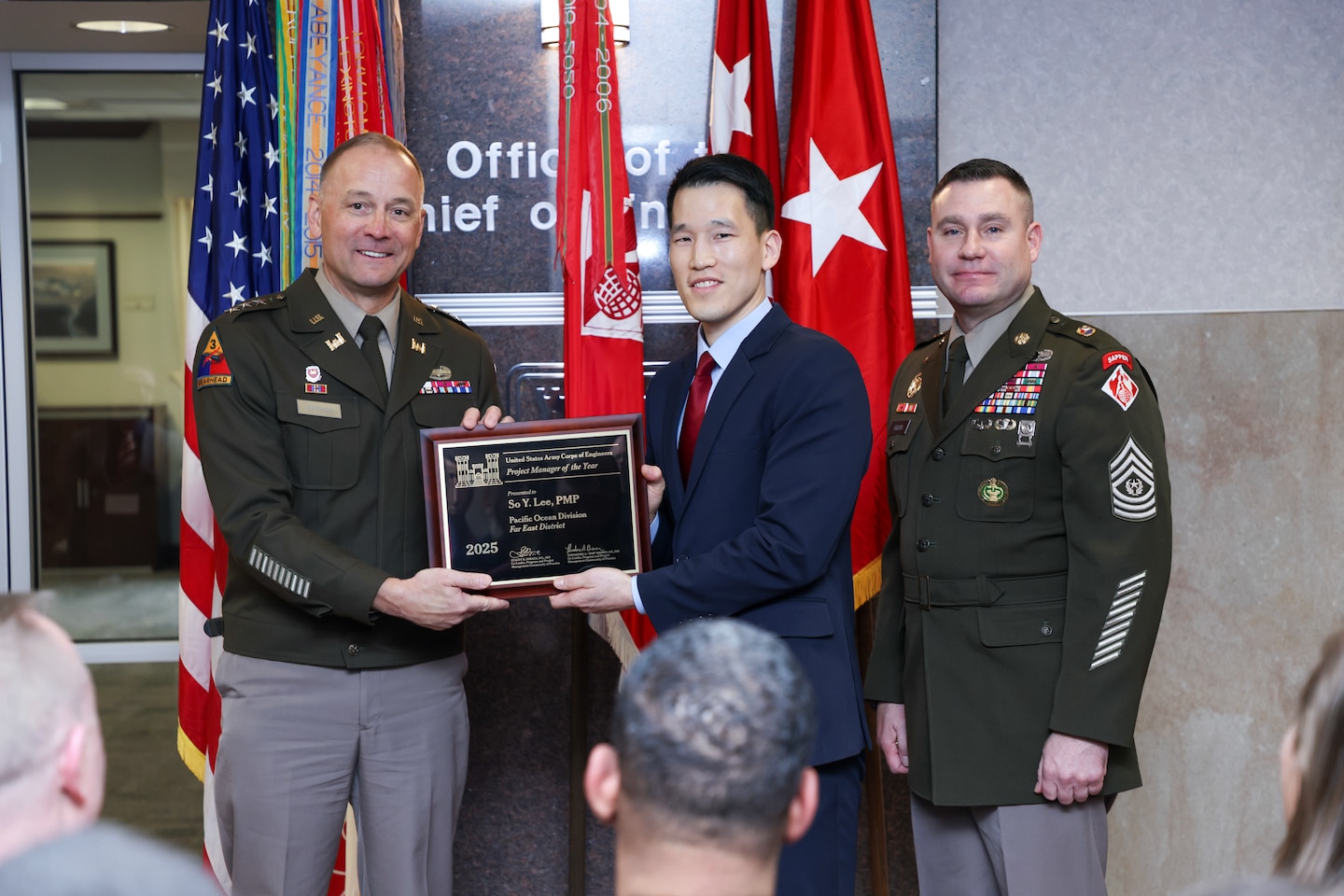 Two soldiers present a man with a plaque.