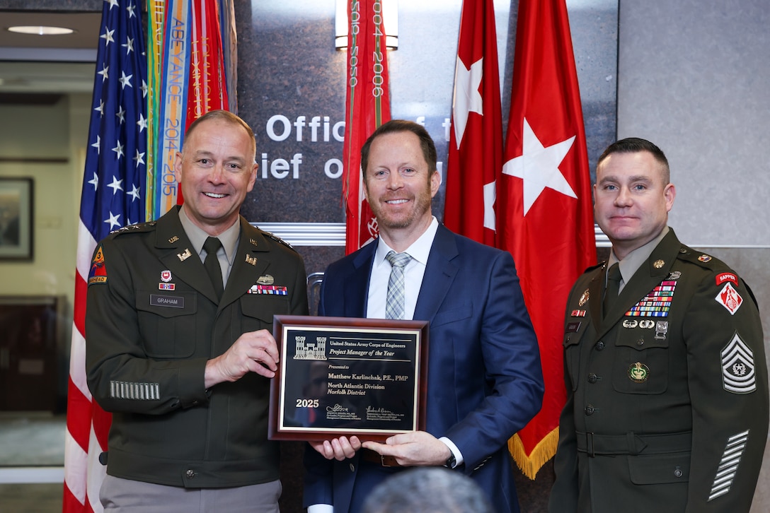 Two soldiers present a man with a plaque.