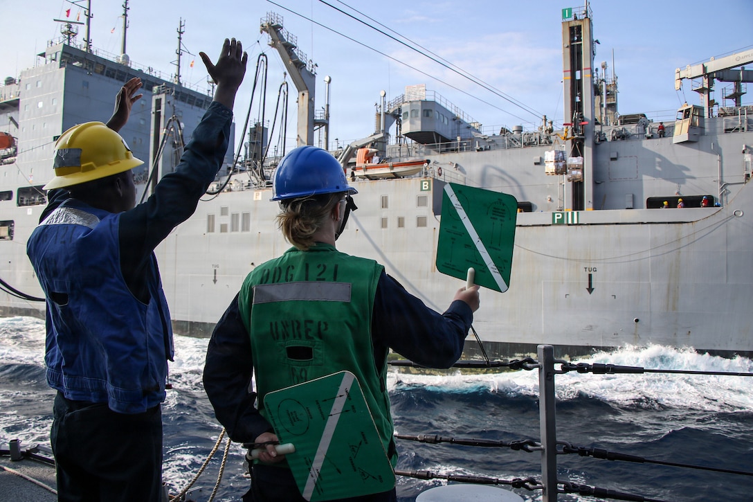 U.S. CENTRAL COMMAND AREA OF RESPONSIBILITY (Jan. 26, 2026) U.S. Navy Boatswain’s Mate 3rd Class Artez Patterson, left, and U.S. Navy Seaman Apprentice Catherine Armitage use signals to load cargo aboard Arleigh Burke-class guided-missile destroyer USS Frank E. Petersen Jr. (DDG 121) during a replenishment-at-sea with Henry J. Kaiser-class fleet replenishment oiler USNS Henry J. Kaiser (T-AO-187) in the U.S. Central Command (CENTCOM) area of responsibility. Frank E. Petersen Jr. is deployed to the U.S. 5th Fleet area of operations to support maritime security and stability in the CENTCOM area of responsibility. (U.S. Navy photo by Mass Communication Specialist 2nd Class Christian Kibler)