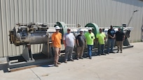 Employees of Naval Undersea Warfare Center Division, Keyport Hawthorne Detachment and members of the operating contractor for Hawthorne Army Depot, pose in front of a mock submarine torpedo tube prototype. The U.S. Department of Defense donated the tube, originally built for a proposed submarine upgrade, to the museum. Left to right: Dakota Baker, Garth Price, Mike Legg, Paul Trujillo, Carlos Isom, Tevis Jones, and Brodie MacPherson. (U.S. Navy photo by Tony Hughes/Released)