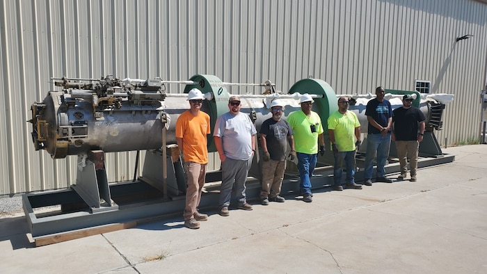 Employees of Naval Undersea Warfare Center Division, Keyport Hawthorne Detachment and members of the operating contractor for Hawthorne Army Depot, pose in front of a mock submarine torpedo tube prototype. The U.S. Department of Defense donated the tube, originally built for a proposed submarine upgrade, to the museum. Left to right: Dakota Baker, Garth Price, Mike Legg, Paul Trujillo, Carlos Isom, Tevis Jones, and Brodie MacPherson. (U.S. Navy photo by Tony Hughes/Released)