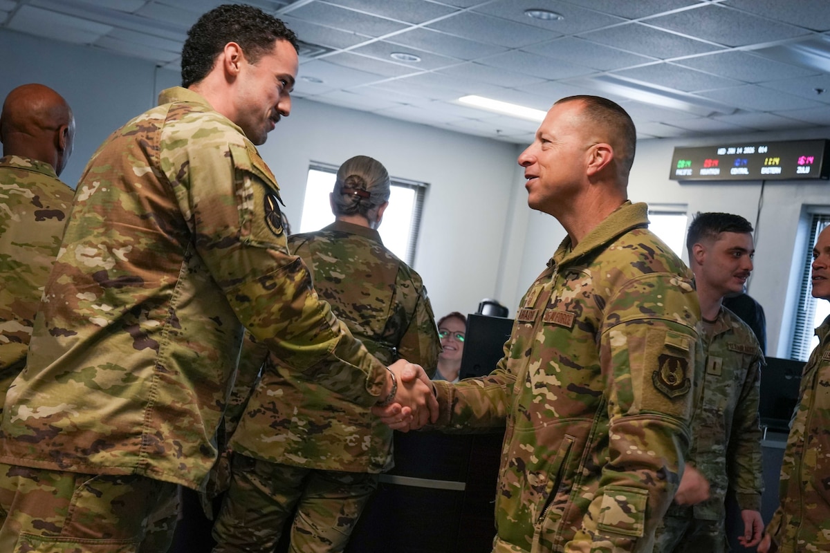Photo shows to uniformed people shaking hands.