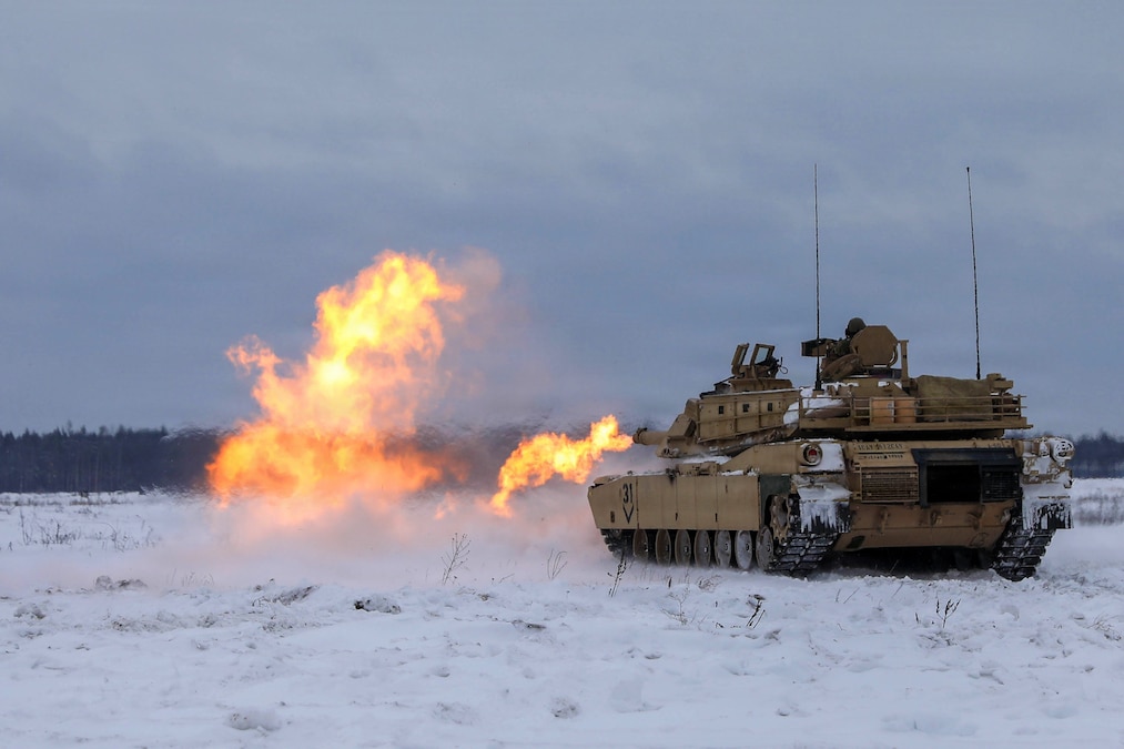 Flames shoot from a tank operating in a snowy field.