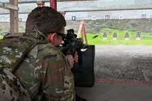 a person in a prone position fires a rifle down a firing range