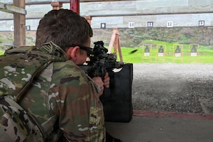 a person in a prone position fires a rifle down a firing range