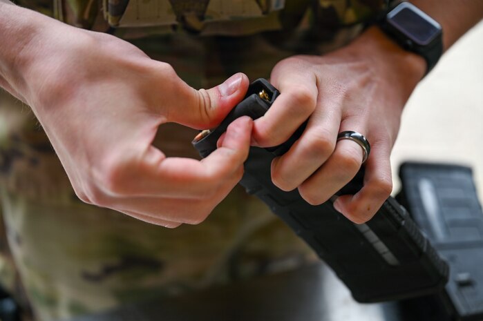 a person loads rounds into a rifle magazine