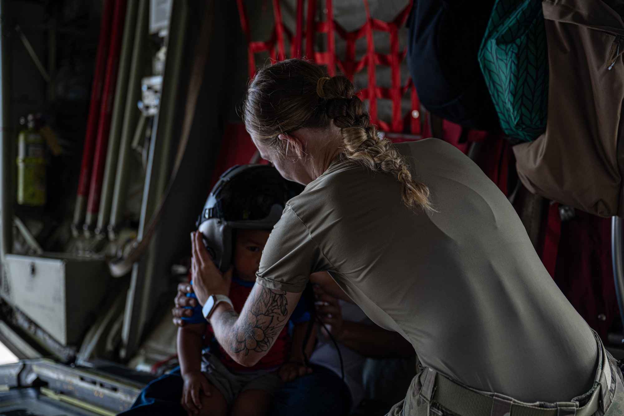 U.S. Air Force Senior Airman Sophia Johnson, 39th Airlift Squadron loadmaster, adjusts a flight helmet on a child during a C-130J Super Hercules static display and community engagement event during Exercise Palmetto Reach at Saipan International Airport, Jan. 20, 2026. Community engagement events foster trust and strengthen relationships between the U.S military and local communities. (U.S. Air Force photo by Airman 1st Class Adrien Tran)