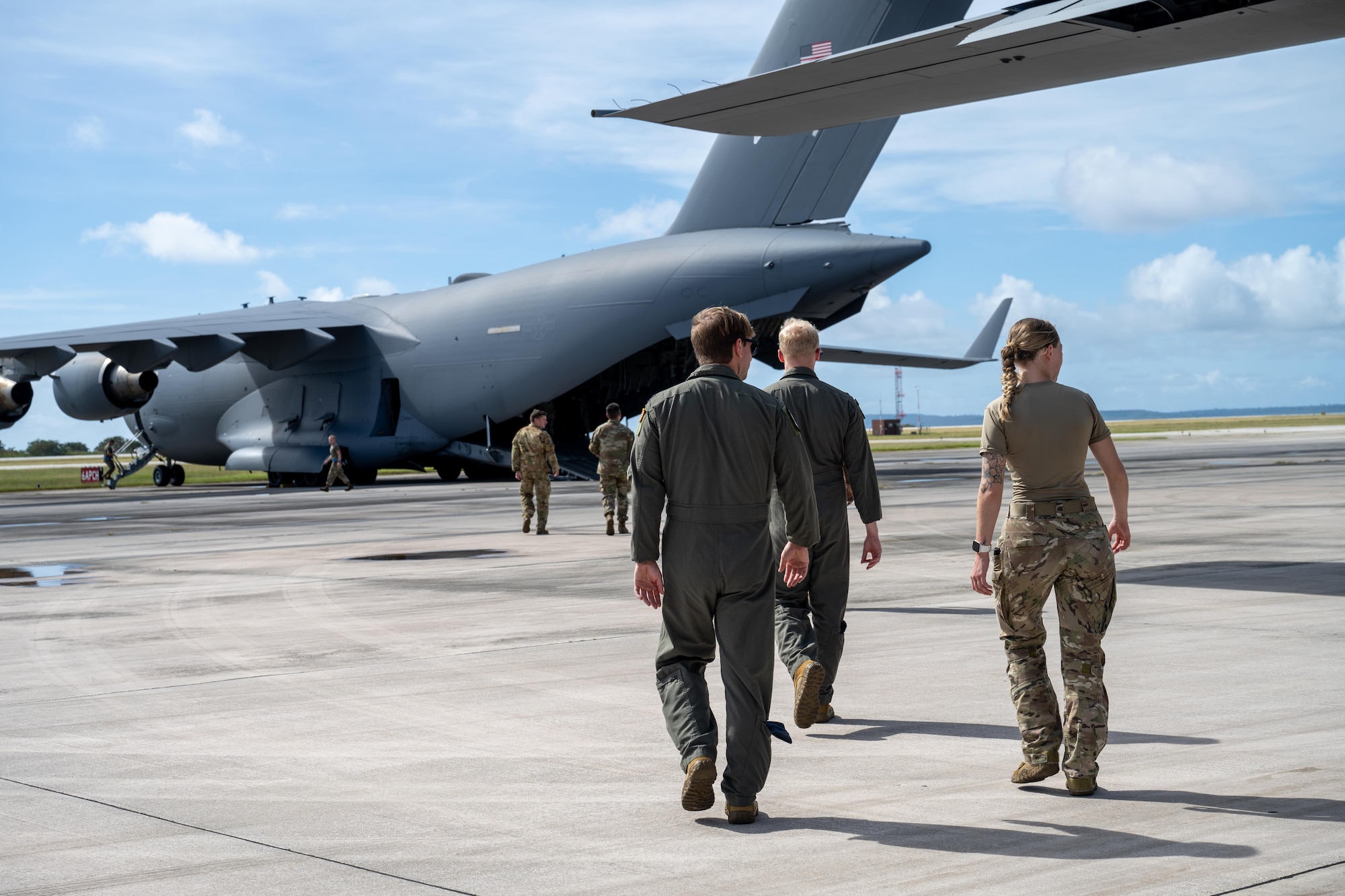 U.S. Air Force Airmen assigned to the 39th Airlift Squadron walk toward a C-17 Globemaster III assigned to the 14th Airlift Squadron prior to a community engagement event during Exercise Palmetto Reach at Saipan International Airport, Jan. 20, 2026. During the exercise, C-130J and C-17 aircrews executed formation flights and joint mission planning, demonstrating how tactical and strategic airlift capabilities complement one another to deliver global mobility effects. (U.S. Air Force photo by Airman 1st Class Adrien Tran)