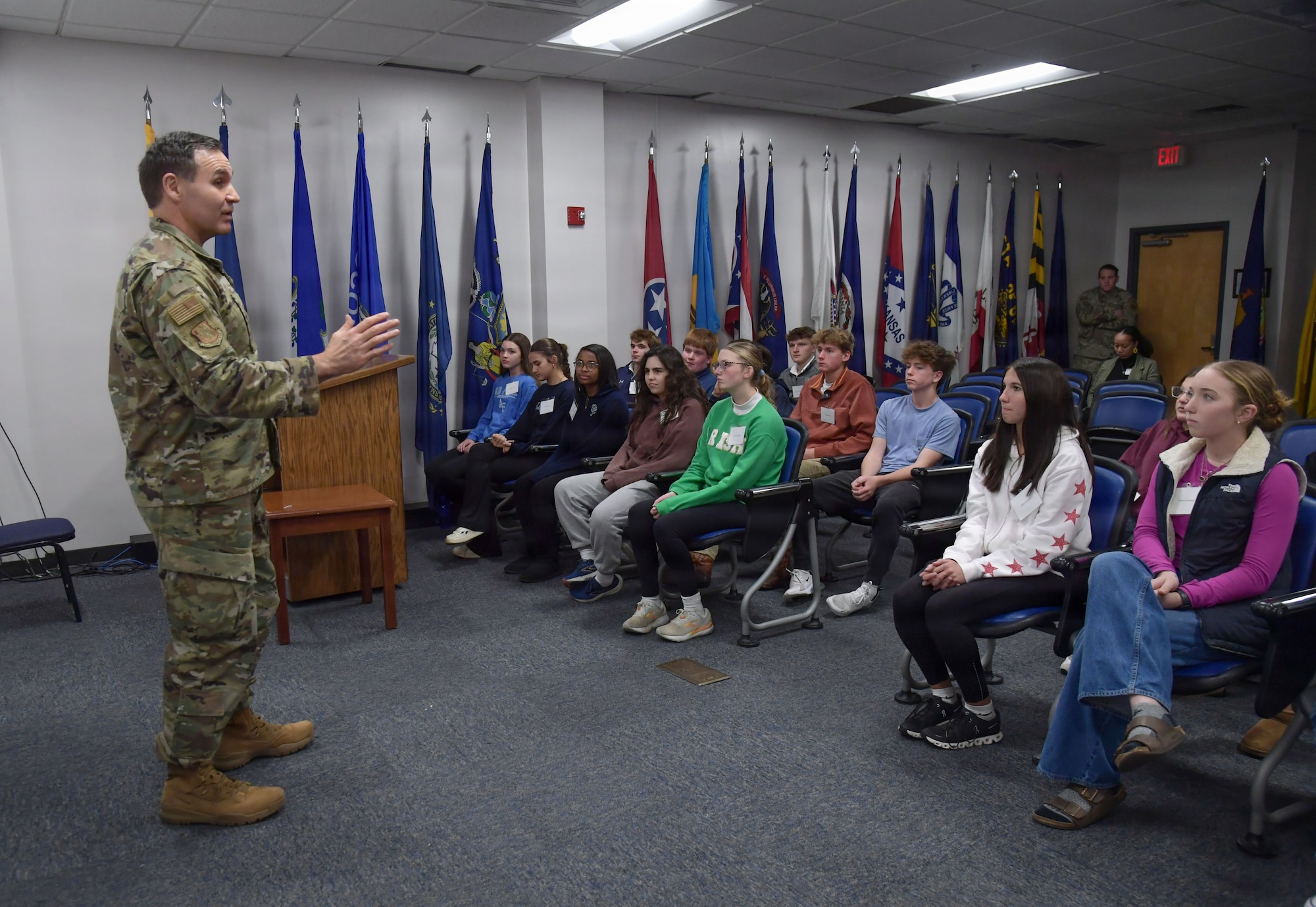 A man in military uniform speaks to students.