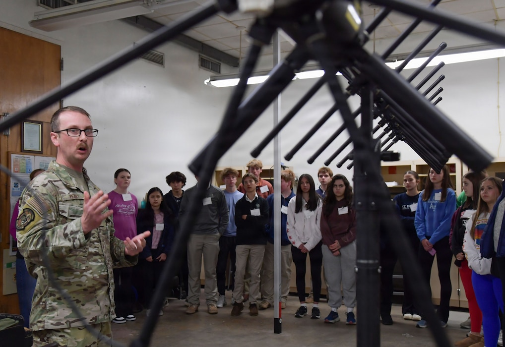 A man refers to a satellite in front of a group of people.