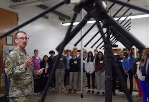 A man refers to a satellite in front of a group of people.