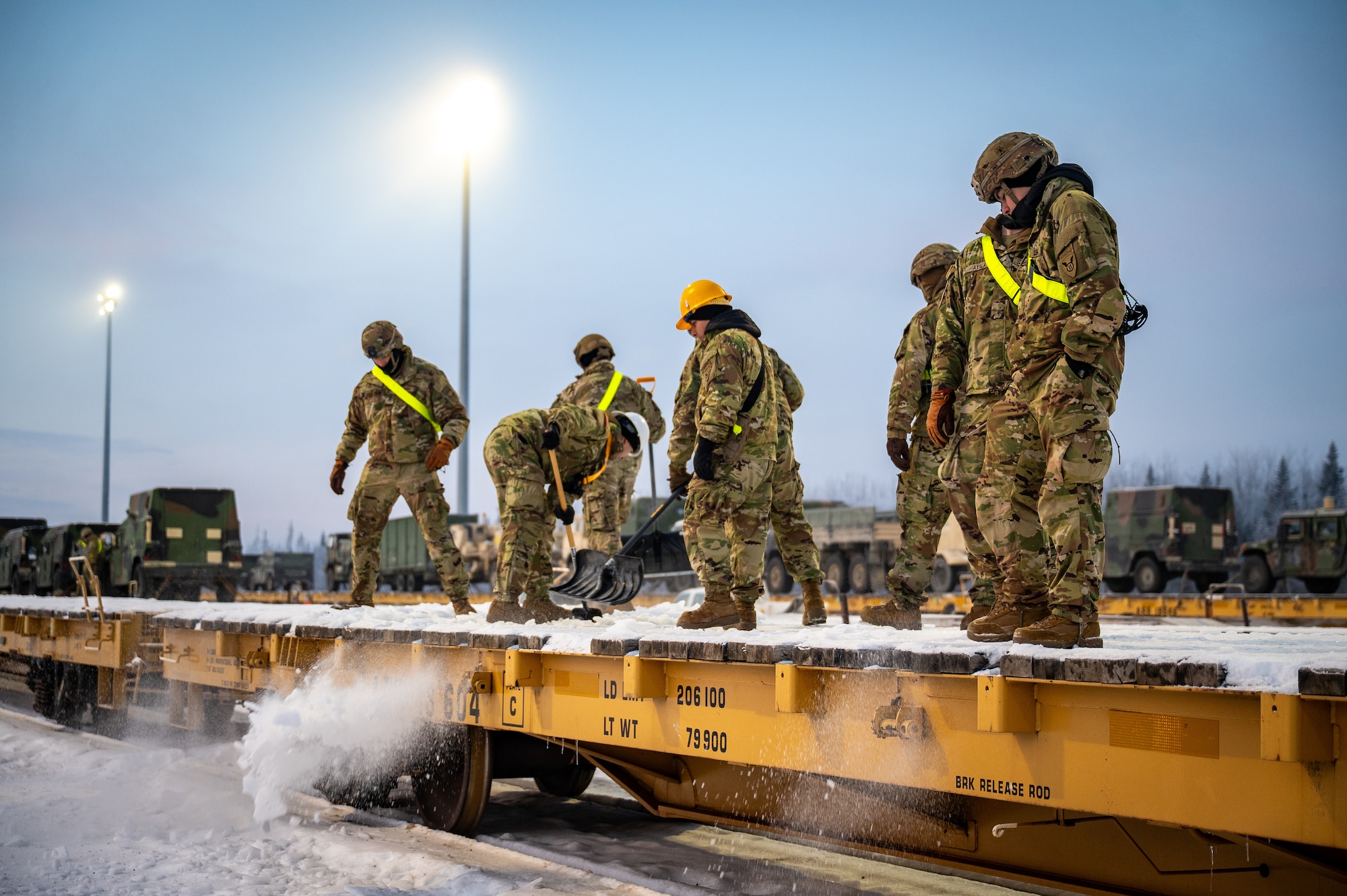 U.S. Army Soldiers assigned to the 3rd Battalion, 509th Parachute Infantry Regiment, 11th Airborne Division, clear snow from a flatcar at Joint Base Elmendorf-Richardson, Alaska, Jan. 22, 2026, in order to load freight in preparation for Joint Pacific Multinational Readiness Center 26-02. Exercise JPMRC is a large-scale training exercise designed to prepare U.S. and allied forces for operations in complex, multi-domain environments. (U.S. Air Force photo by Senior Airman Hunter Hites)