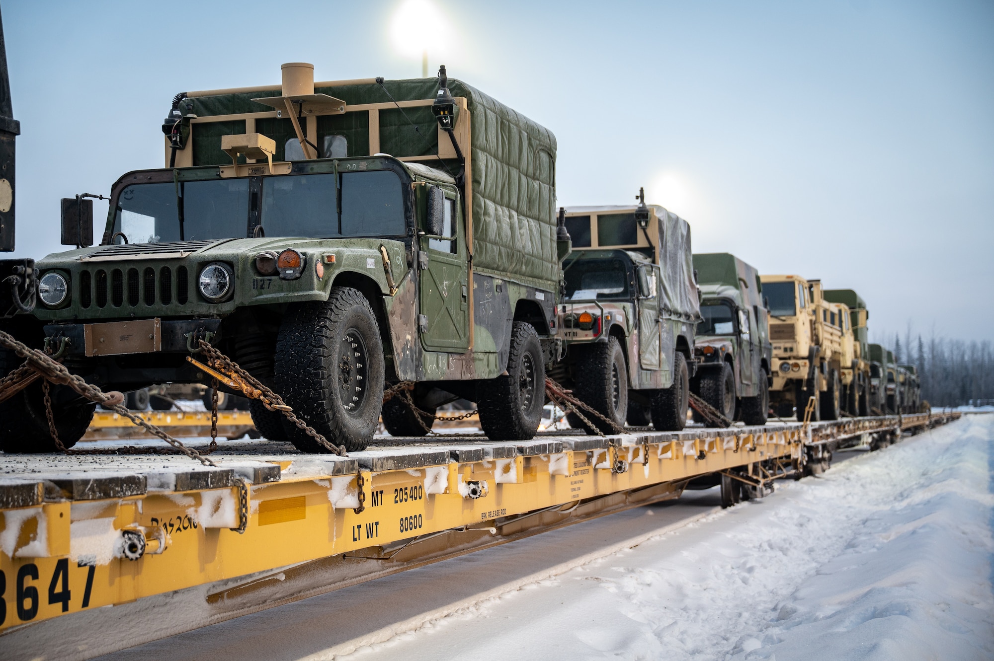Vehicles sit after being loaded onto a flatcar at Joint Base Elmendorf-Richardson, Alaska, Jan. 22, 2026, in preparation for Joint Pacific Multinational Readiness Center 26-02. Exercise JPMRC is a large-scale training exercise designed to prepare U.S. and allied forces for operations in complex, multi-domain environments. Rail loading enables the rapid movement of personnel and equipment, ensuring unit readiness and the ability to deploy efficiently for large-scale training exercises. (U.S. Air Force photo by Senior Airman Hunter Hites)