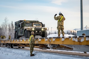 U.S. Army Soldiers assigned to the 3rd Battalion, 509th Parachute Infantry Regiment, 11th Airborne Division, direct vehicles onto a flatcar at Joint Base Elmendorf-Richardson, Alaska, Jan. 22, 2026, for Joint Pacific Multinational Readiness Center 26-02. The exercise tests units’ ability to deploy, integrate and operate effectively across the Indo-Pacific region. (U.S. Air Force photo by Senior Airman Hunter Hites)