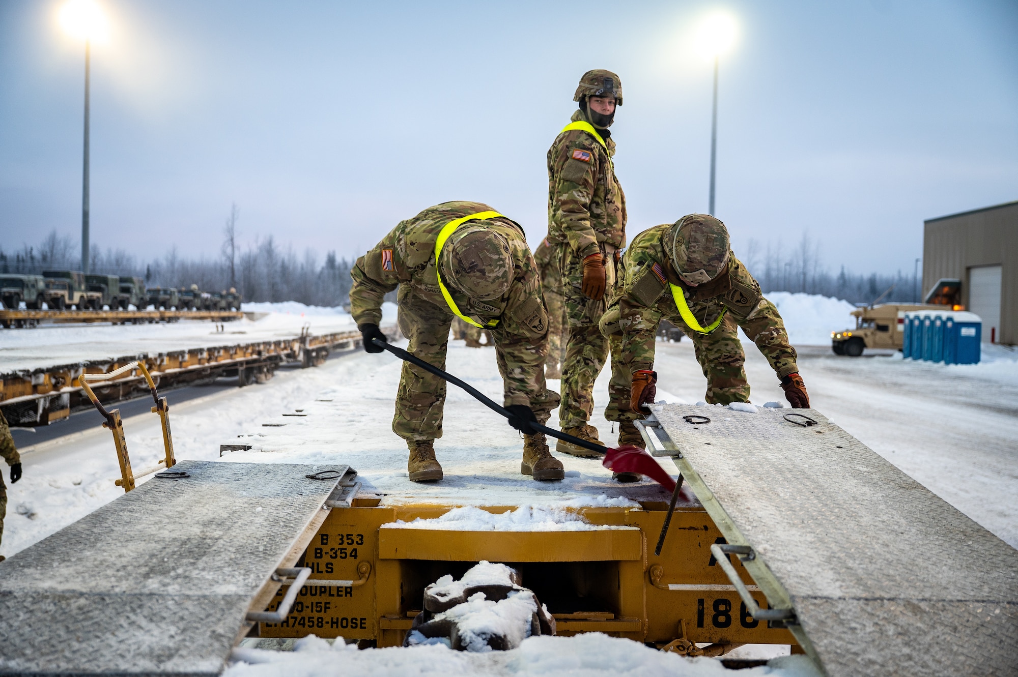 U.S. Army Soldiers assigned to the 3rd Battalion, 509th Parachute Infantry Regiment, 11th Airborne Division, clear snow from a flatcar at Joint Base Elmendorf-Richardson, Alaska, Jan. 22, 2026, in order to load freight in preparation for Joint Pacific Multinational Readiness Center 26-02. The exercise tests units’ ability to deploy, integrate and operate effectively across the Indo-Pacific region. (U.S. Air Force photo by Senior Airman Hunter Hites)