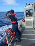 U.S. Coast Guard Seaman Marquis Turner, a deck department member assigned to Coast Guard Station Kauai in Lihue, Hawaii, uses binoculars to search for a man in the water off the north shore of Kauai Jan. 30, 2026. Coast Guard and agency partners are searching for a man in the water who was swept off the rocks while fishing near Kahili Beach. (U.S. Coast Guard photo, courtesy Station Kauai)