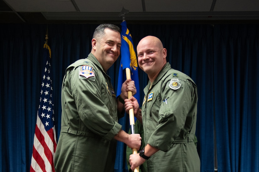 Lt. Col. Josh Ketterer, right, accepts the 123rd Operations Group guidon from Col. Matthew Quenichet, 123rd Airlift Wing commander, during a change-of-command ceremony at the Kentucky Air National Guard Base in Louisville, Ky., Dec. 14, 2025. Ketterer replaces Col. Randall Hood, who was named deputy commander of the 123rd Airlift Wing. (U.S. Air National Guard photo by Tech. Sgt. Chloe Ochs)