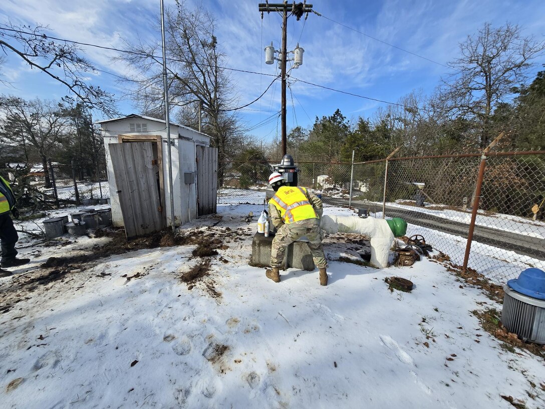 a soldier looks at snow covered equipment