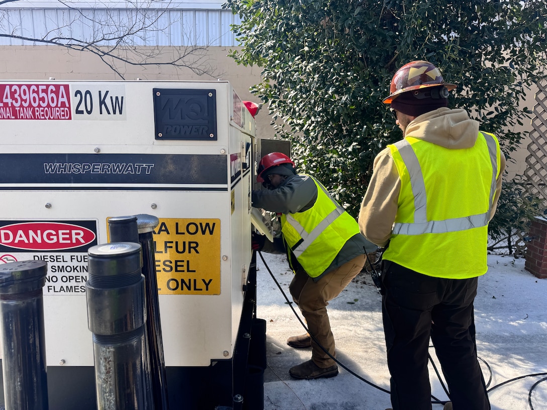A man is working on a generator while another looks on.