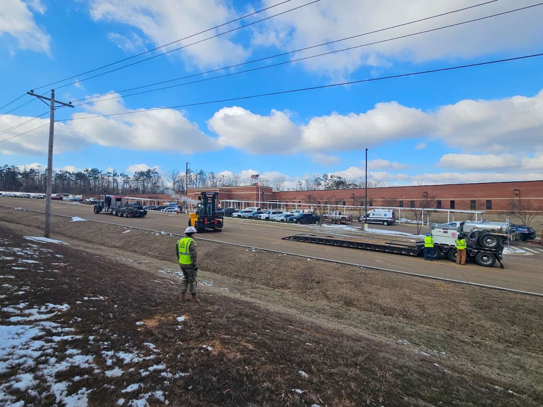 A forklift is moving towards a large fuel tank on the back of a trailer.