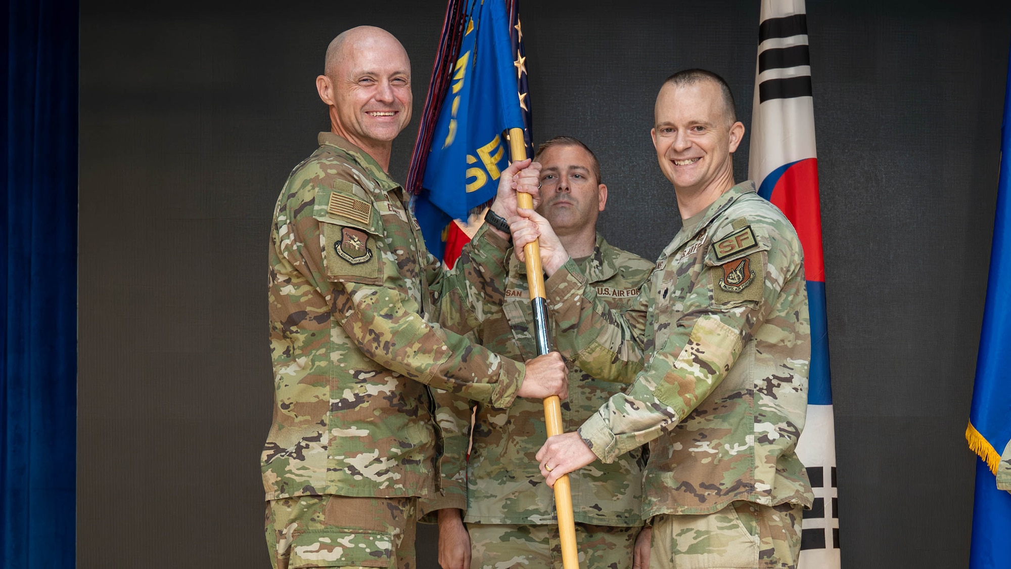 U.S. Air Force Lt. Col. Daniel Evans, outgoing 51st Security Forces Squadron commander, relinquishes command of the 51st SFS to  Col. Jeff Elliott, left, 51st Mission Support Group commander, during a change of command ceremony at Osan Air Base, Republic of Korea, June 26, 2026. The 51st SFS is the largest Security Forces unit in the Pacific Air Forces, defending and guarding more than $18 billion dollars in Protection level 1 through 4 resources and over 13,000 personnel. (U.S. Air Force photo by Senior Airman Megan Cusmano)