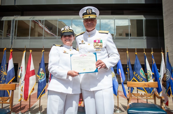 Rear Adm. Kevin J. Brown, commander, Naval Medical Forces Pacific, and director, Defense Health Network Pacific Rim, presents the Legion of Merit to Capt. Elizabeth Adriano, outgoing director of Naval Medical Center San Diego (NMCSD), during the Navy Medicine Readiness and Training Command (NMRTC) San Diego change of command and NMCSD transfer of directorship ceremony at the hospital, June 30, 2026. NMRTC San Diego supports Navy and Marine Corps readiness by ensuring its medical forces are ready to deploy and provide medical support, ashore or at sea. The mission of NMCSD is to optimize health and enhance readiness. NMCSD employs more than 5,500 active-duty military personnel, civilians, and contractors in southern California to deliver exceptional care afloat and ashore. (U.S. Navy photo by Mass Communication Specialist 1st Class Marcus Stanley)