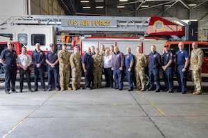 A photo of the 628th Civil Engineer Squadron Fire Prevention team standing together for a photo. The team is in a large garage with a fire truck in the background.