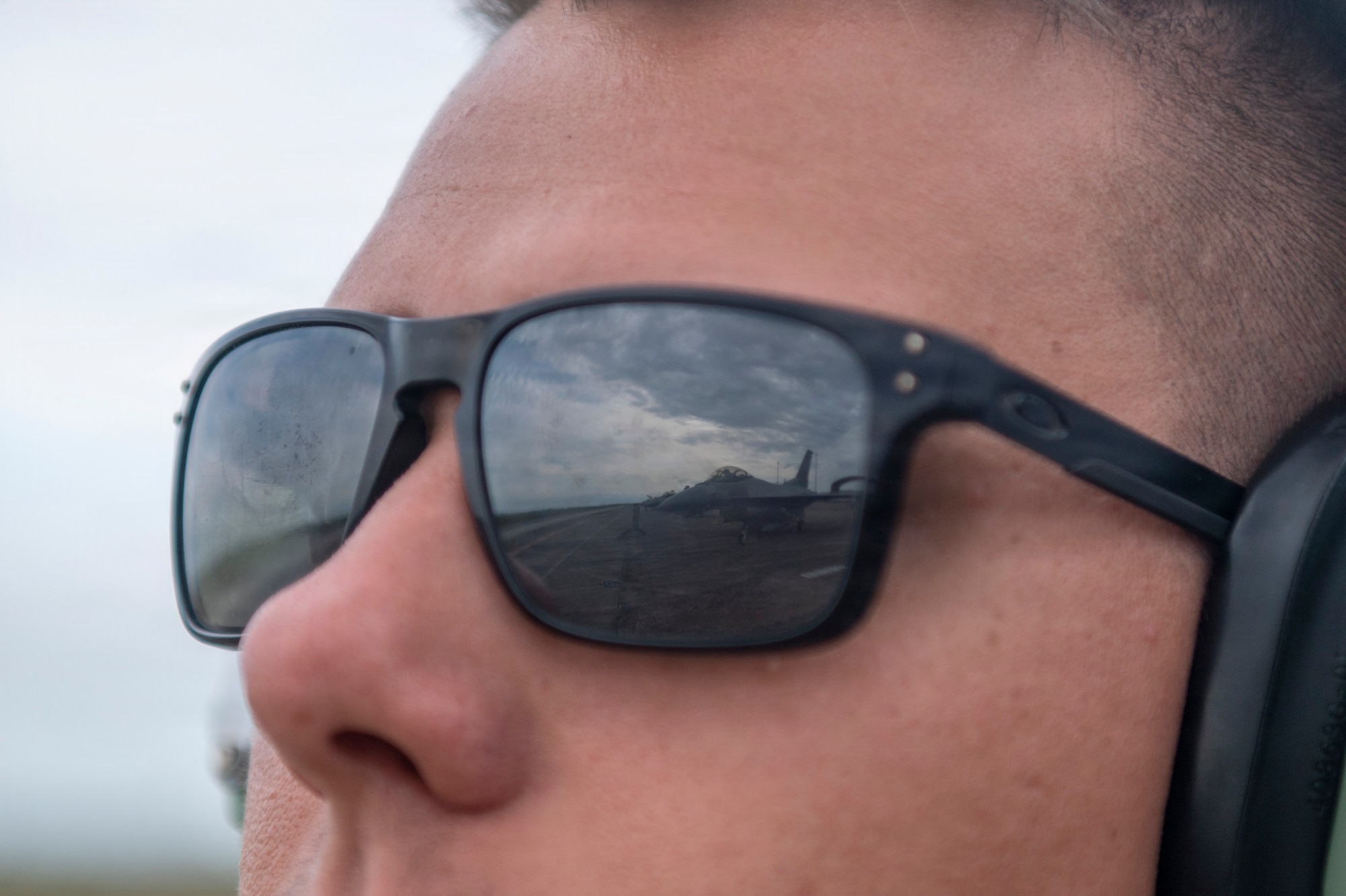 plane in reflection of a mans glasses