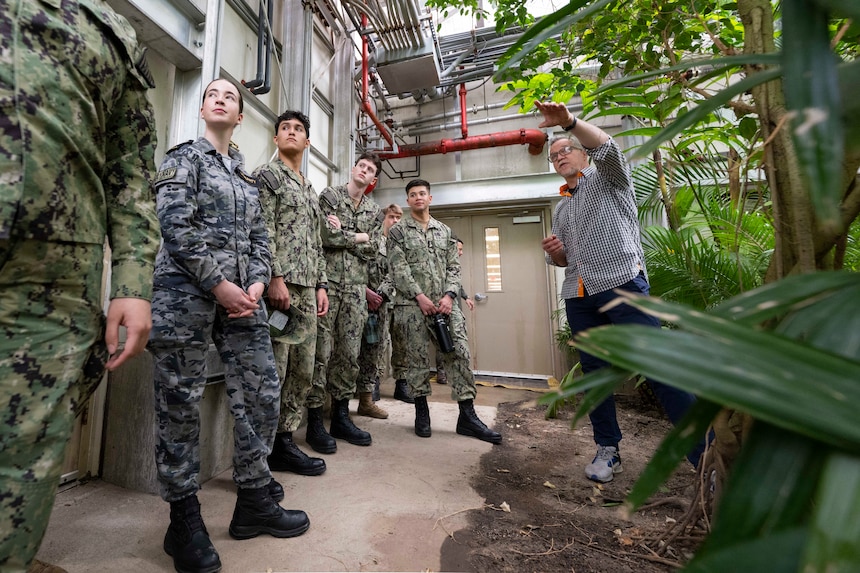Allen O’Hara, facility manager for the U.S. Naval Research Laboratory's (NRL) Laboratory for Autonomous Systems Research (LASR), leads midshipmen from the U.S. Naval Academy Physics Club on a tour of NRL’s Tropical High Bay in Washington, March 25, 2026. The unique facility allows researchers to test new technology against real-world environmental conditions, ensuring naval systems are reliable and ready for deployment. (U.S. Navy photo by Sarah Peterson) RELEASED