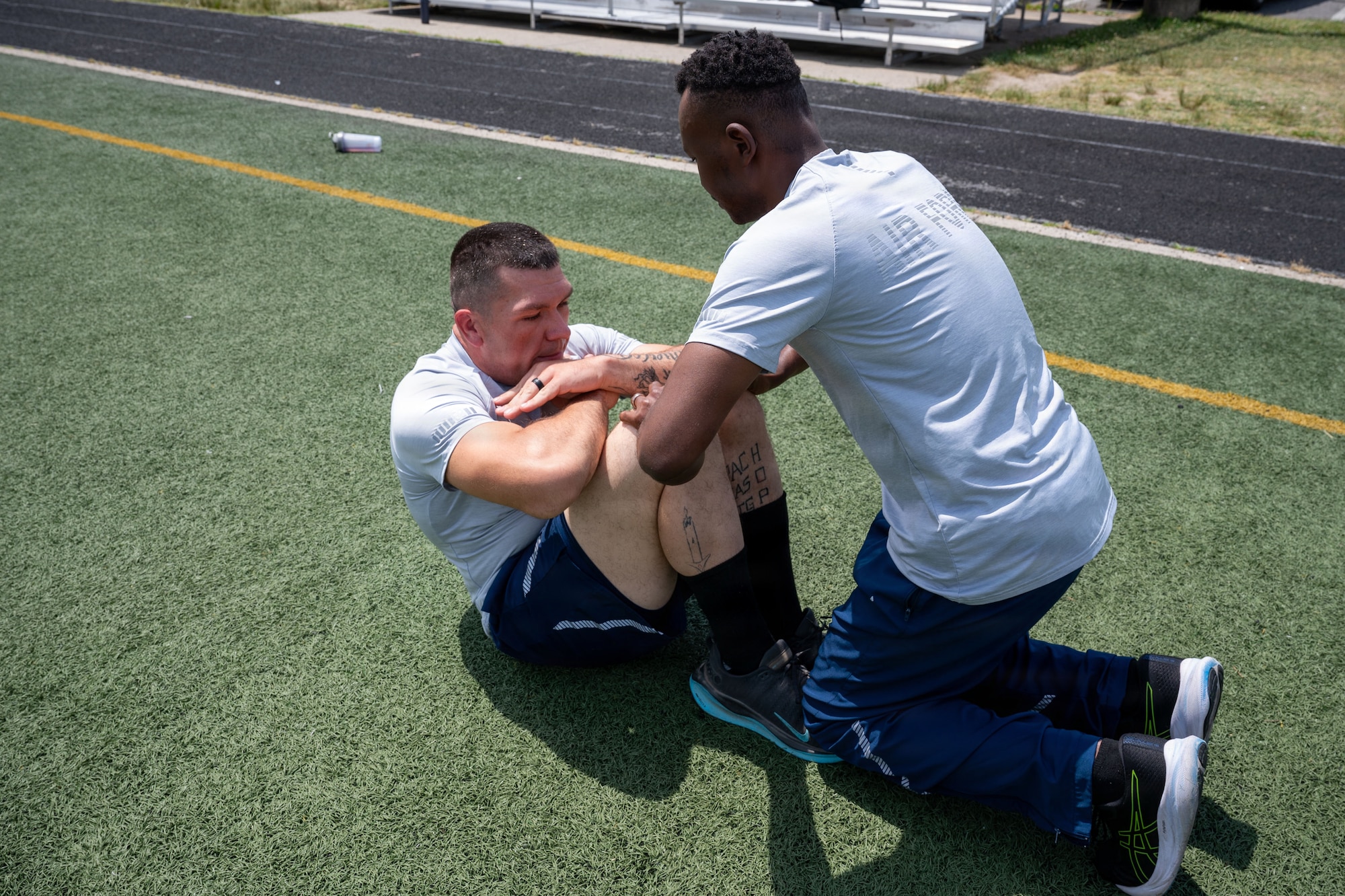 U.S. Air Force Airman 1st Class Phillip Lukas and Airman 1st Class Frederic Epee Wang Dipanda demonstrate proper sit-ups.