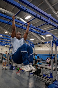U.S. Air Force Senior Airman Austin Mwandoe, financial operations technician assigned to the 316th Comptroller Squadron, executes high knee tucks.