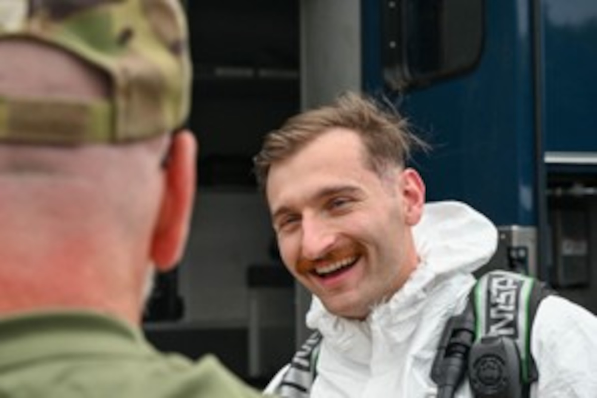 A man smiles while talking to another man