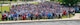 A large group of people predominantly wearing red, white, and blue pose for a photo on a lawn area.