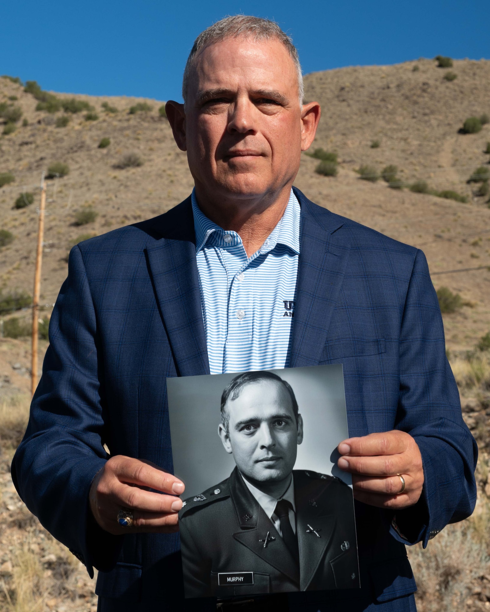 Retired U.S. Navy Cmdr. Douglas Murphy holding a memento of his late father in front of the Manzano Mountains at Kirtland Air Force Base, New Mexico, June 26, 2026.