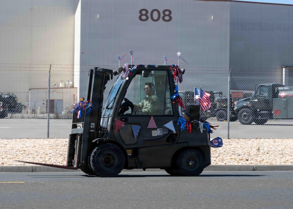 A decorated forklift drives by in a parade.