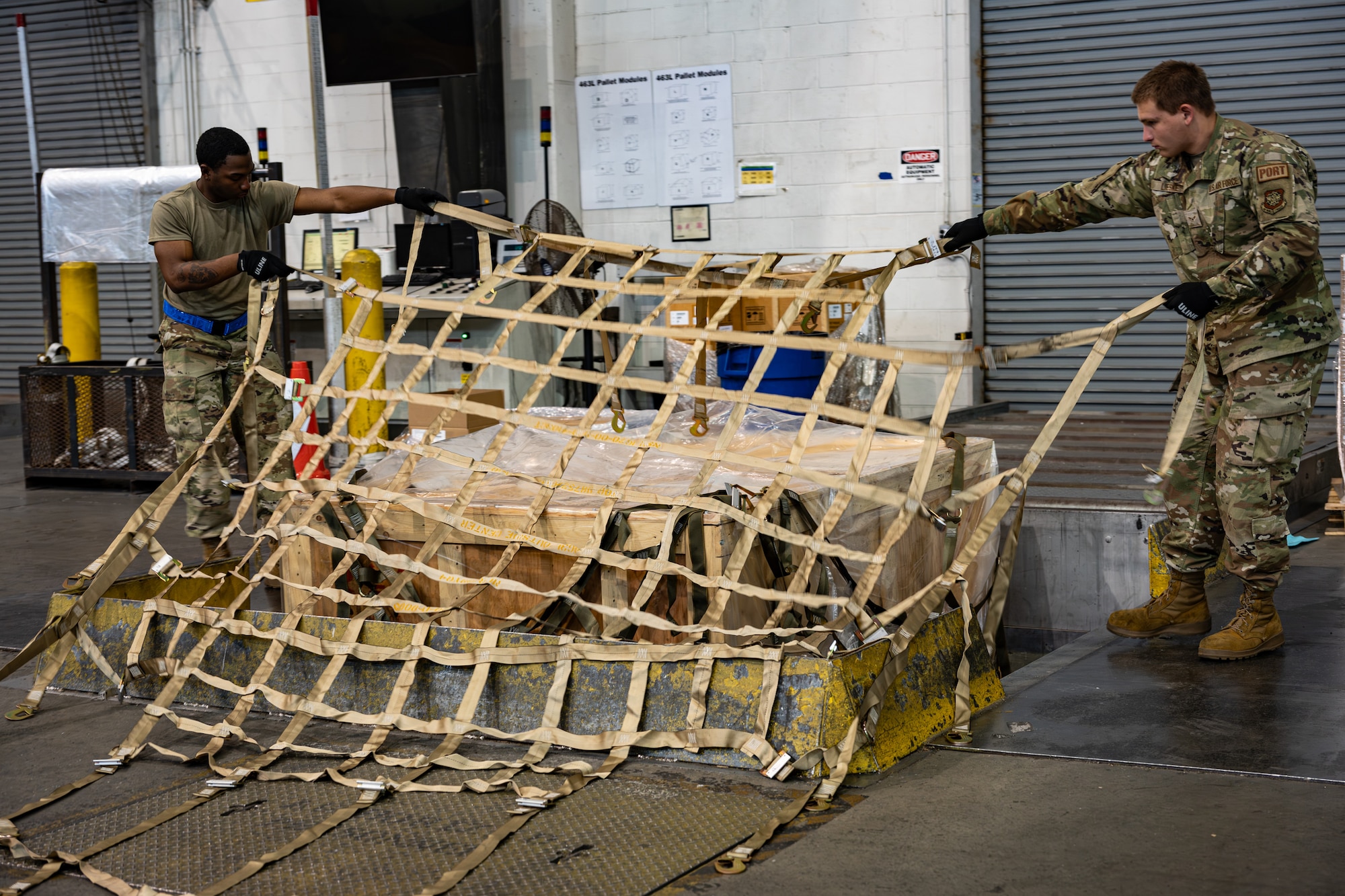 U.S. Air Force Airmen Clark Bote and Airman 1st Class Andrew Lieske, 436th Aerial Port Squadron processors, pull the netting to secure a pallet before shipment on Dover Air Force Base, Delaware, June 24, 2026.