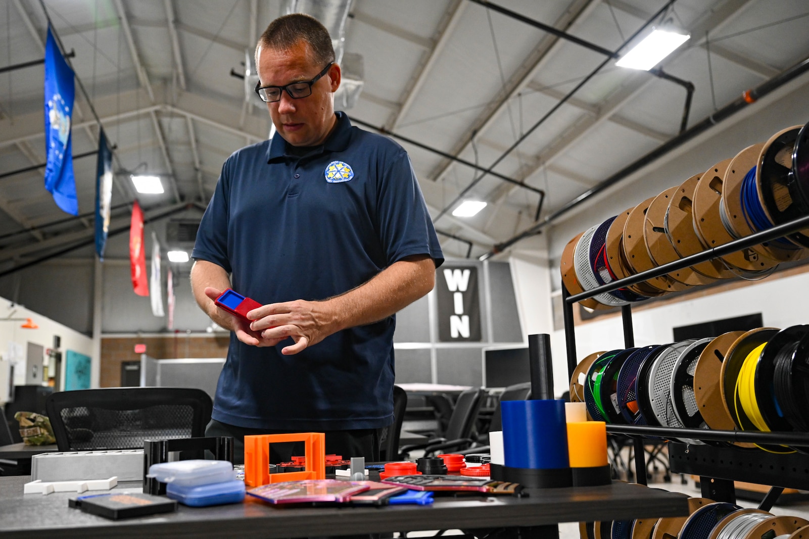 A man stands at a table with a 3D printed object in his hands.