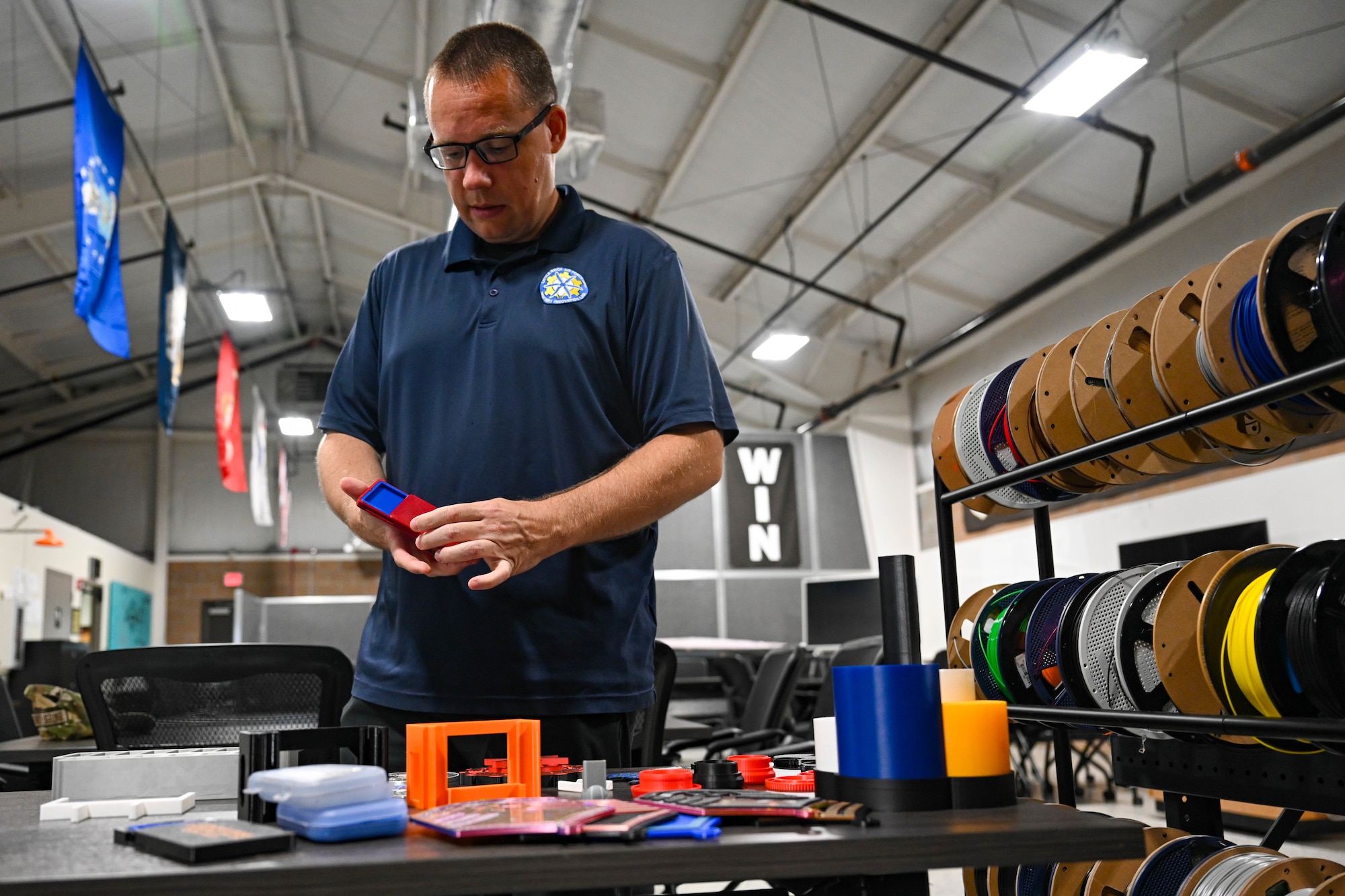 A man stands at a table with a 3D printed object in his hands.