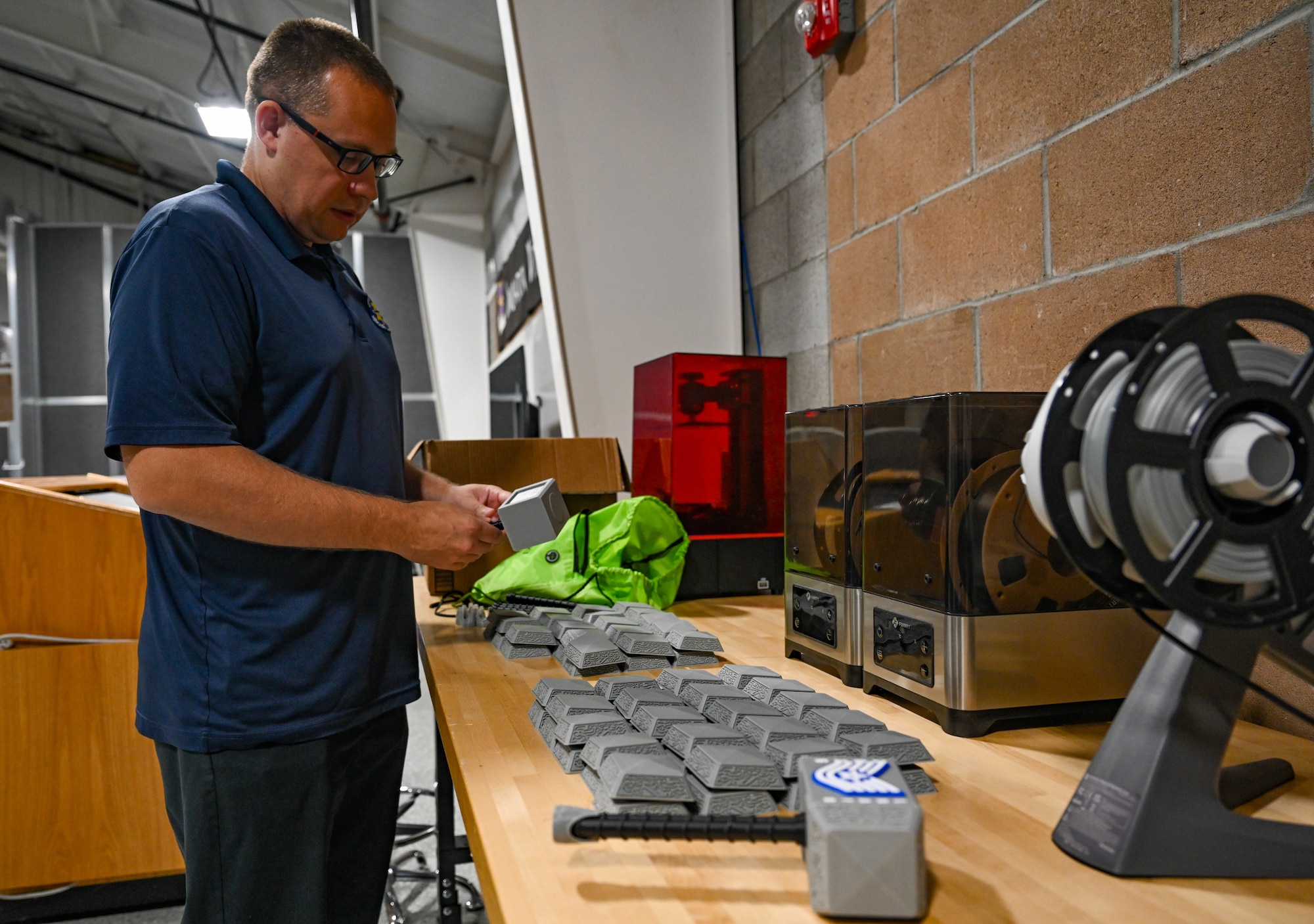 A man stands at a table and assembles a 3D printed object.