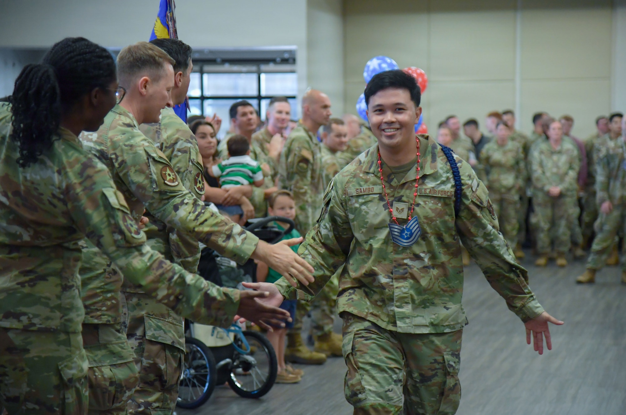 A man in U.S. Air Force military uniform gives a hi-five to other Airmen.