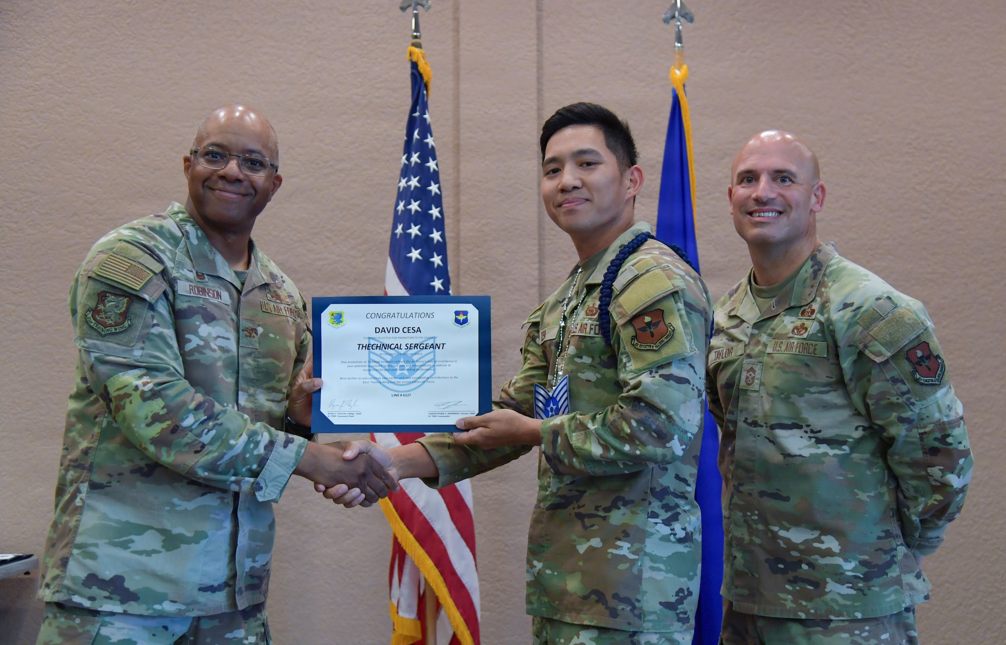 A man in U.S. Air Force military uniform presents a certificate to an Airman.
