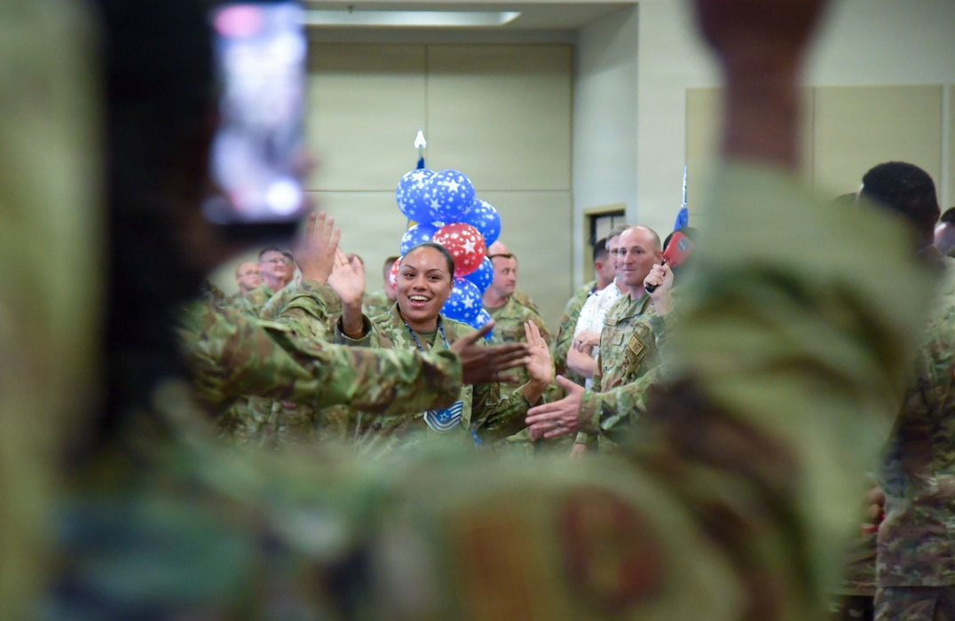 A woman in U.S. Air Force military uniform hi-fives other Airmen.