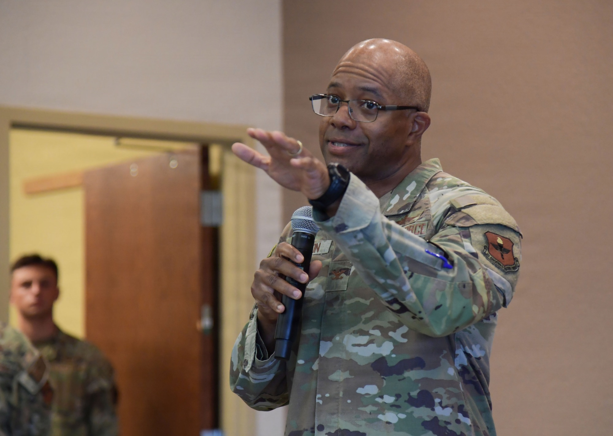 A man in U.S. Air Force military uniform speaks into a microphone.