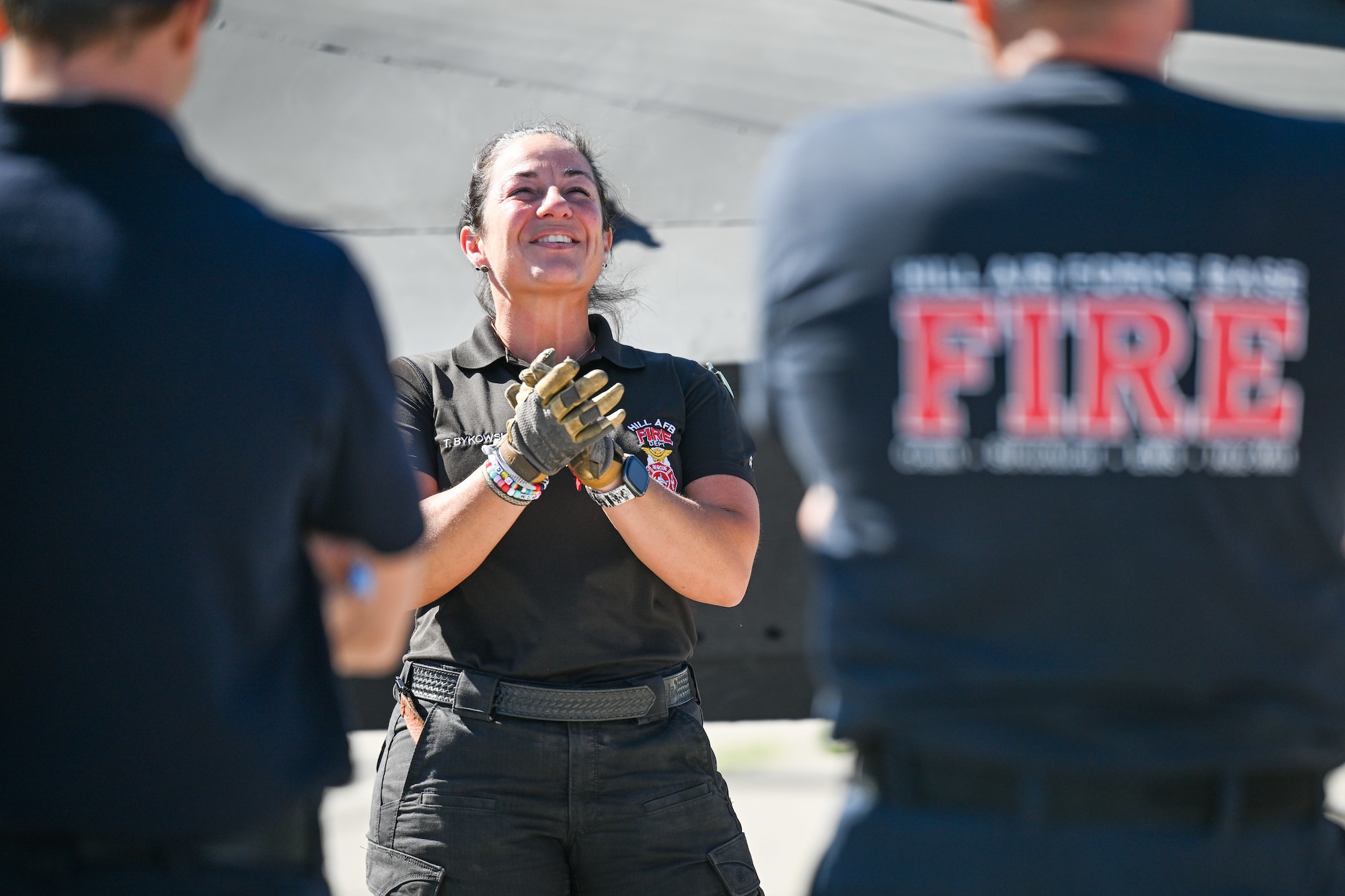 Female firefighter smiling and clapping hands outdoors during training
