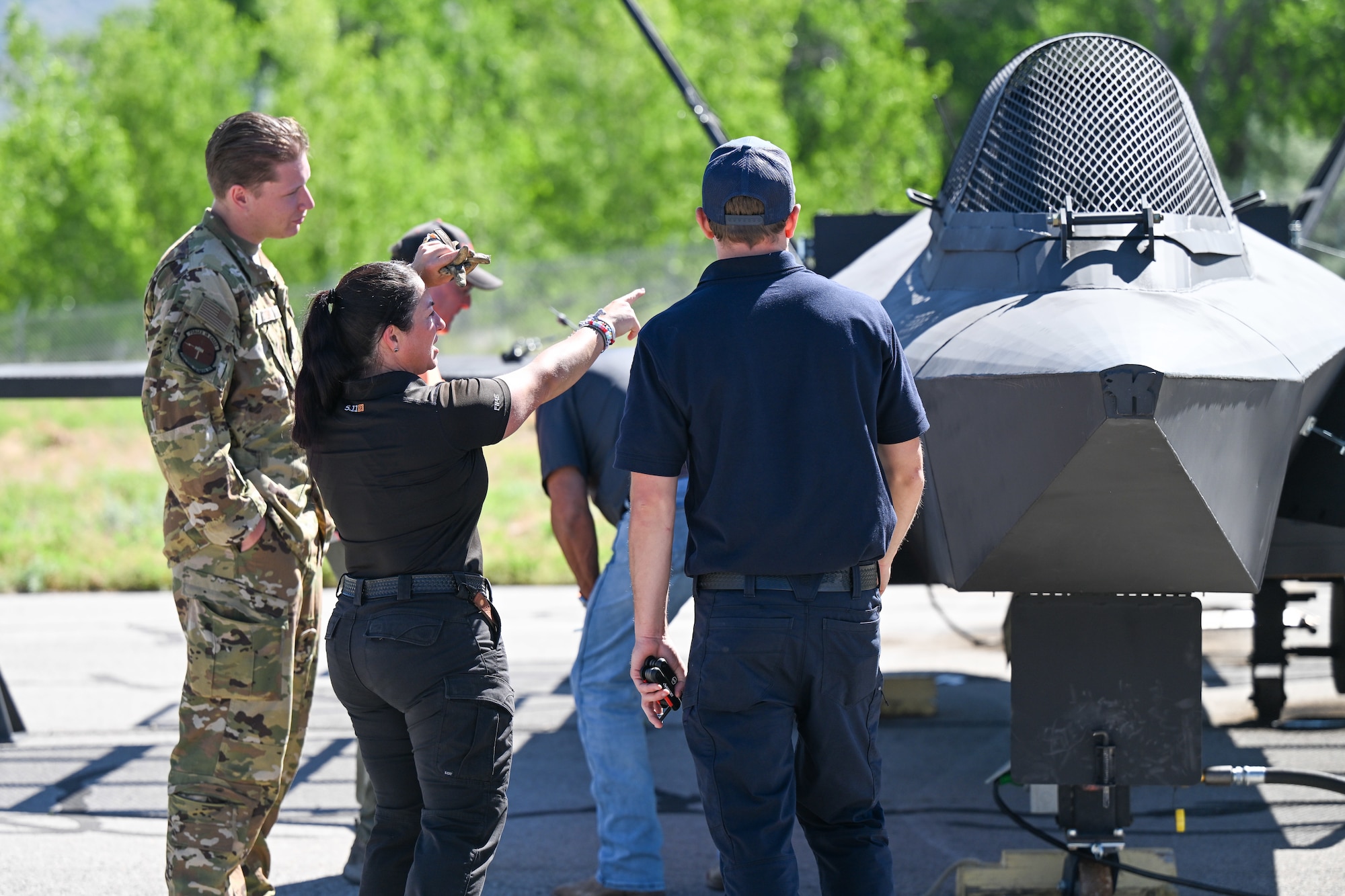 4 military personnel and civilians examine a aircraft used to train firefighters