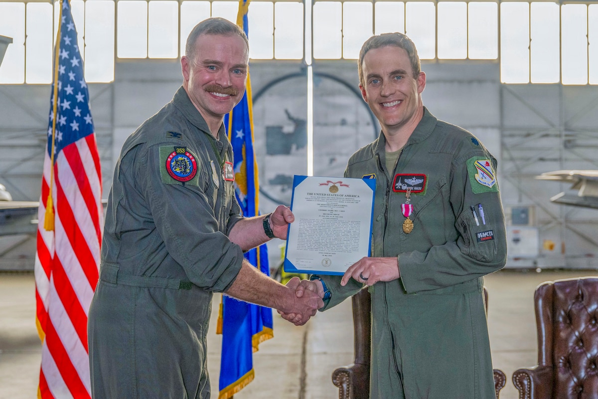 U.S. Air Force Lt. Col. Eric Hakos, 353rd Combat Training Squadron commander, right, receives the Meritorious Service Medal from U.S. Air Force Col. Samuel Chipman, 354th Operations Group commander, during a change of command ceremony at Eielson Air Force Base, Alaska, June 26, 2026.