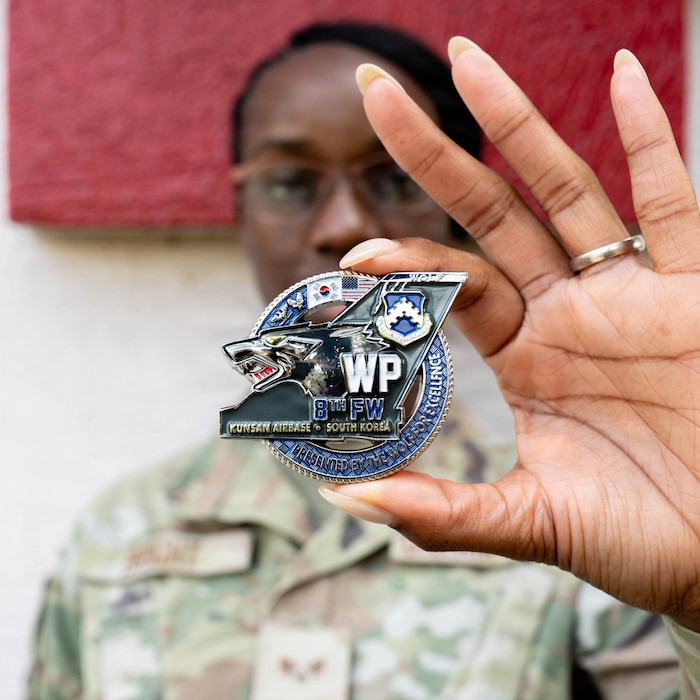 Airman holds coin.