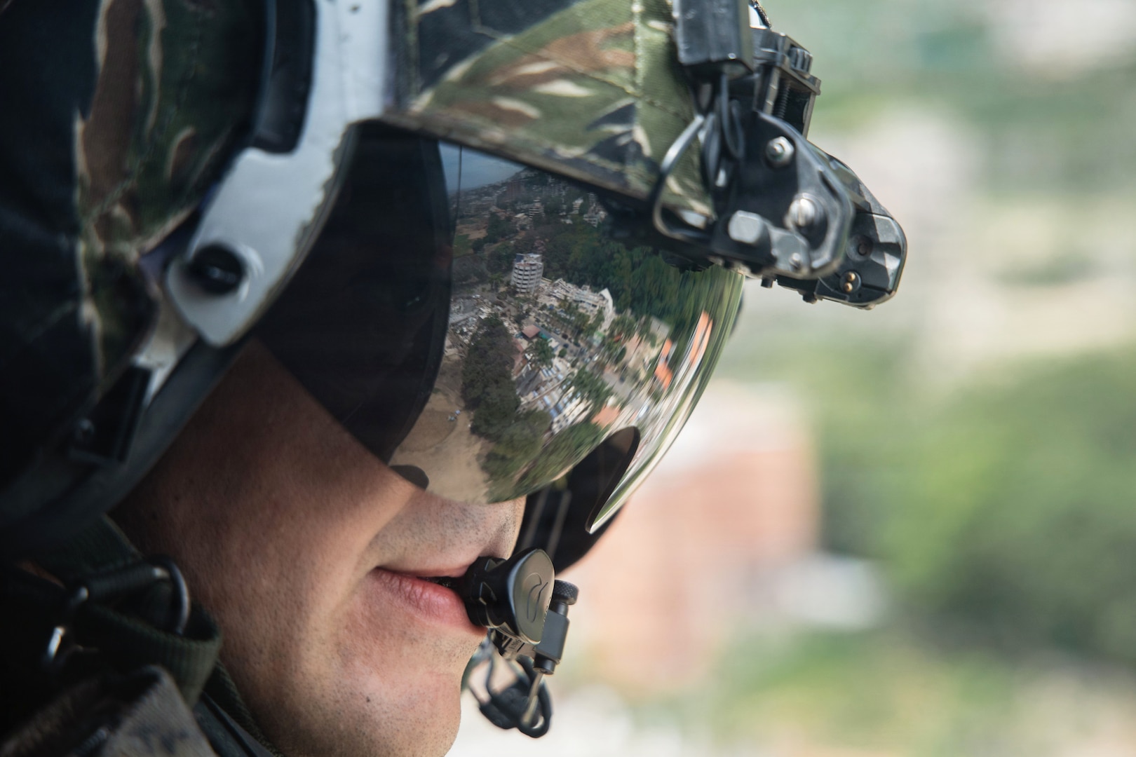 A close-up of a Marine Corps helicopter crew chief wearing a headset and reflective glasses.