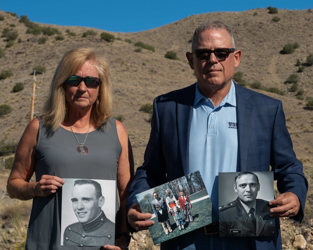 Retired U.S. Navy Cmdr. Douglas Murphy and his wife, Helen Murphy, hold momentos of Murphy’s late father in front of the Manzano Mountains at Kirtland Air Force Base, New Mexico, June 26, 2026.
