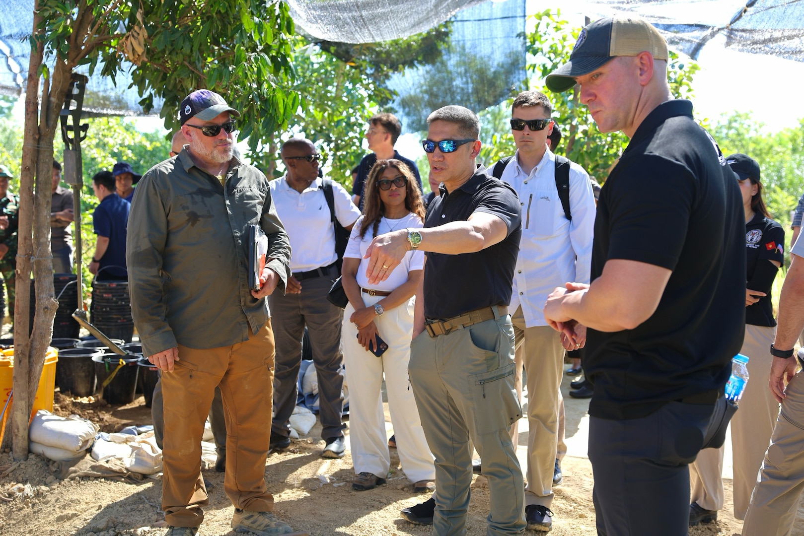 Three individuals discuss recovery operations in the field.